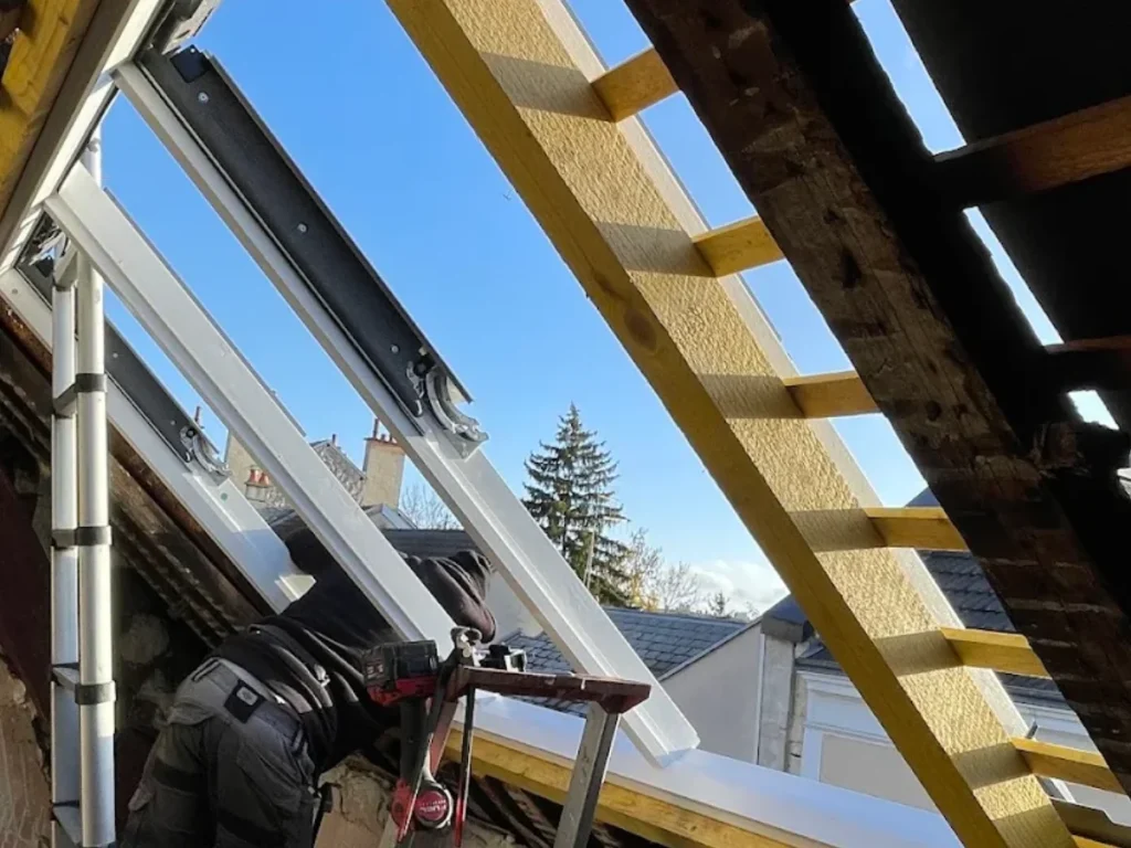 Pose d'une fenêtre de toit sur charpente neuve, toiture ouverte, couvreur au travail